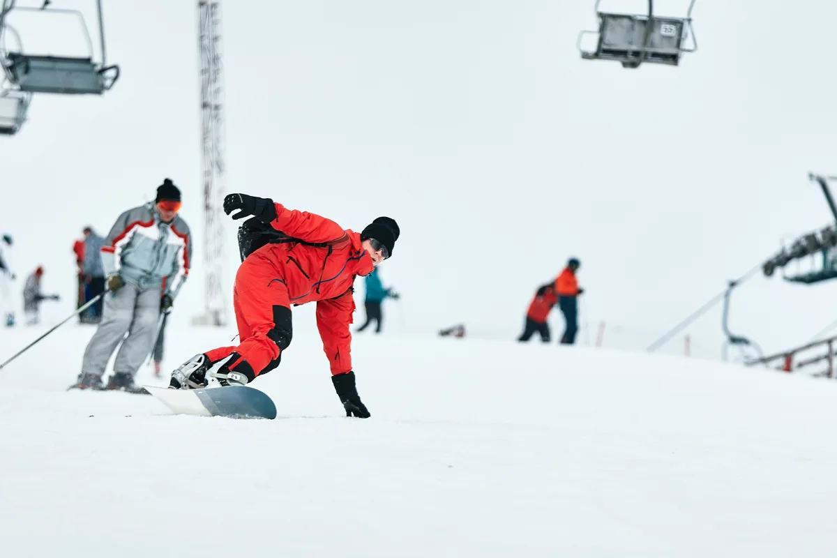 Erciyes snowboard dersinde eğitmenin yetişkine kenar kontrolü öğretmesi